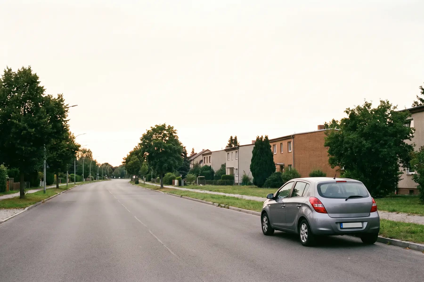 Symbolbild: ruhige Wohnstraße mit geparktem Auto unter weitem Himmel